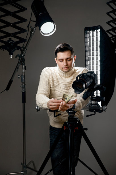 摄影师，三脚架上的数码相机，手里拿着百元大钞图片下载