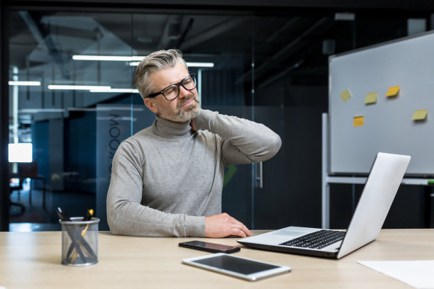 一个疲惫不堪的商人，在办公室里抱着自己的脖子，用手按摩自己的脖子图片下载