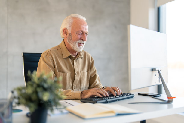 年长的白发商人使用电脑，在办公室打字工作，写电子邮件图片下载