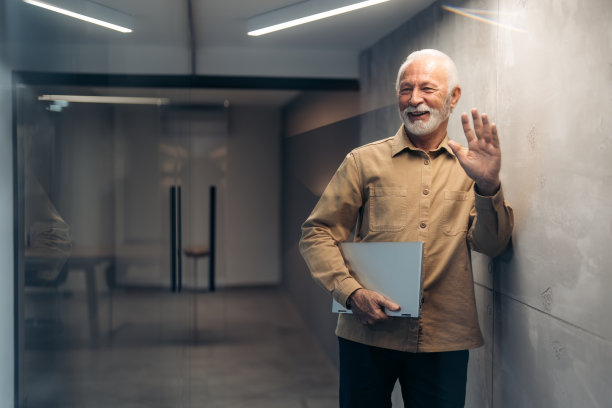 快乐微笑的白发大胡子公司领导站在现代化的办公大楼图片下载
