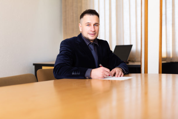 一位商人坐在办公室的谈判桌前签署文件图片下载