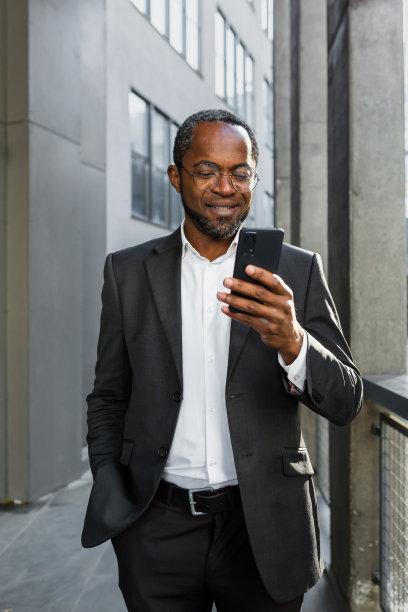 一个非裔美国商人站在办公室附近。使用电话，打电话，打字图片下载
