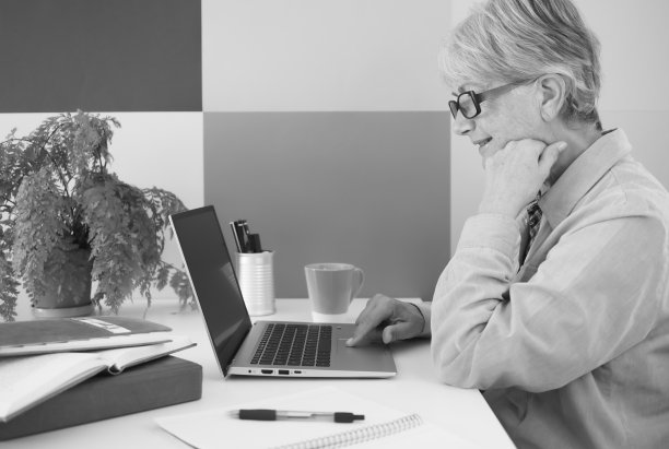 白人有吸引力的妇女戴着黑色眼镜坐在办公室使用笔记本电脑。女商人在线，网上银行，无线技术。本空间图片下载