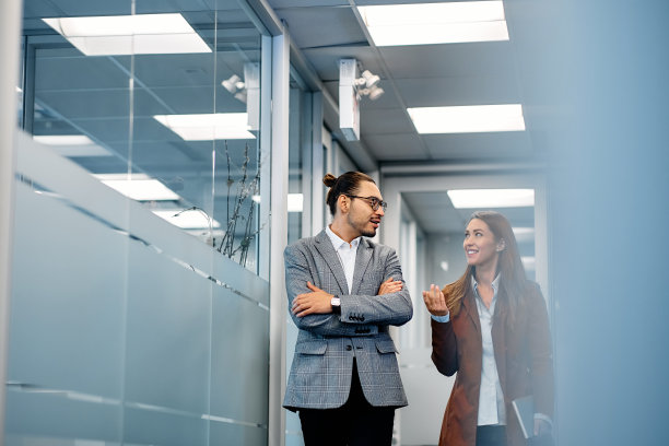 愉快的商务同事在办公室走廊里闲聊。图片下载
