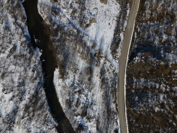 在塞尔维亚，无人机在冬天穿过被雪、岩石、树木和河流覆盖的山丘和山脉的道路上拍摄的照片图片下载