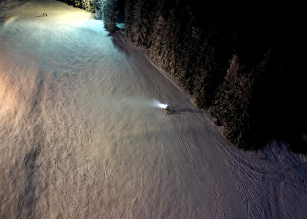 从高处观察滑雪者在下坡道上的行为。水炮人工造雪。把一股水流射到有凹槽的表面上。昂贵的能源密集型技术图片下载
