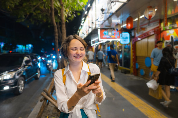 一个拿着智能手机的女人晚上走在城市里图片下载
