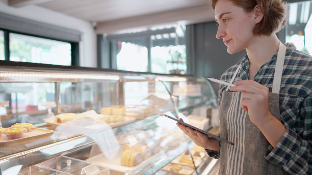 企业家或员工走到检查咖啡制作原料和面包店准备接待和服务客户。年轻女性创业的老板或经理在咖啡店工作，检查面包店的冰柜前。图片下载