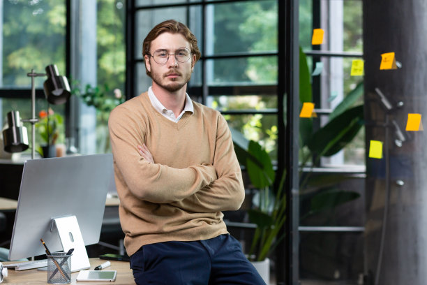 一个年轻的自由职业者，程序员，设计师在办公室，交叉着双臂，看着镜头图片下载