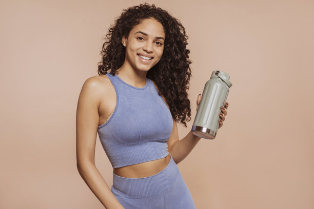 美丽的多种族女运动员在工作室摆姿势拿着水瓶图片下载