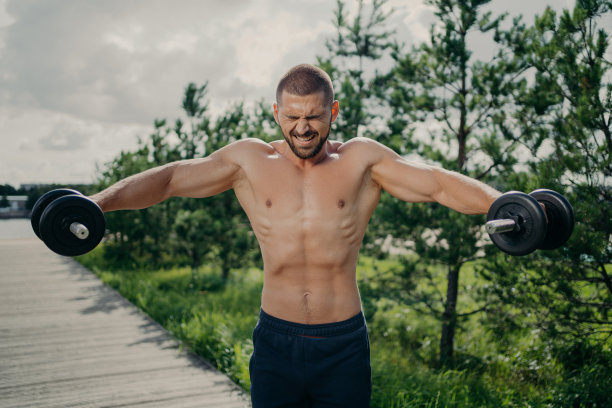 肌肉强壮的运动员展示耐力，举起沉重的杠铃和训练手臂肌肉，在户外赤裸上身，全力以赴地举重。运动员用哑铃锻炼图片下载
