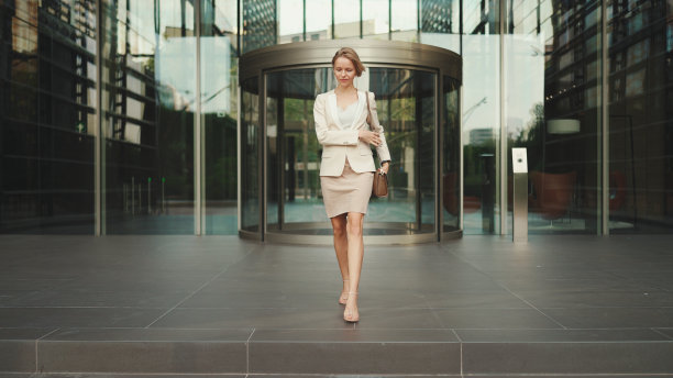 身着米色西装的金发女商人离开商业中心图片下载