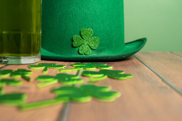 绿色的帽子，三叶草，硬币和桌上的一杯啤酒。圣帕特里克节。图片下载