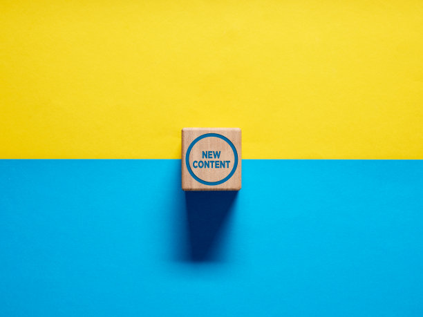 文字新内容的木质立方体按下按钮在蓝色和黄色的背景。图片下载