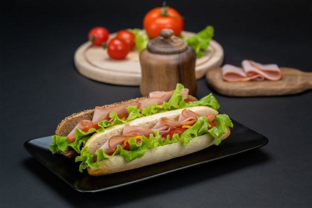美味的三明治配火腿、切达干酪和蔬菜，放在黑色盘子里图片下载