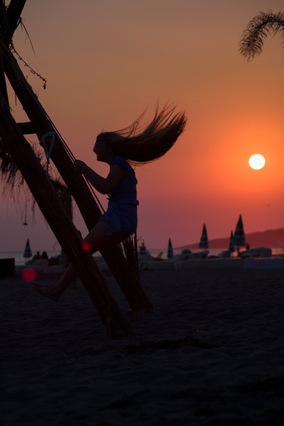 一个年轻女孩在沙滩上荡秋千的剪影图片下载