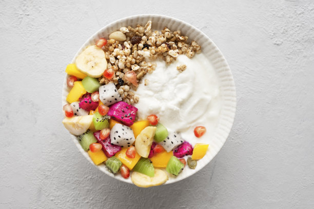 热带水果酸奶碗的俯视图与格兰诺拉麦片，芒果，猕猴桃，香蕉，火龙果和石榴浅灰色背景图片下载