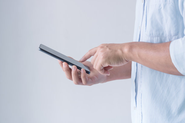 年轻的商人拿着智能手机发短信，时髦的男人在白色背景下输入触摸屏手机。商业、生活方式、科技和社交媒体网络。图片下载