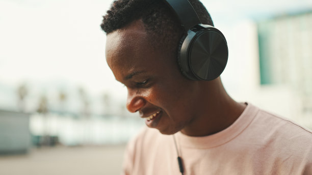 一个年轻的非洲学生戴着耳机坐在大学外面图片下载