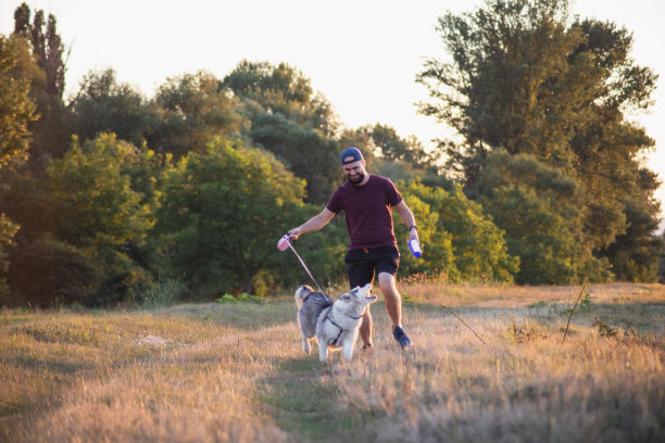 年轻男子与他的哈士奇狗跑在阳光明媚的早晨在大自然图片下载