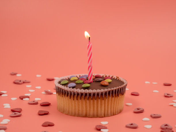 粉色背景上有蜡烛的松饼。假日松饼。图片下载