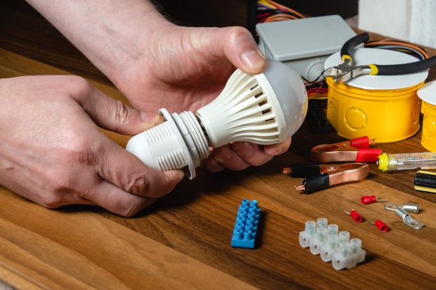 电工师傅把灯泡打开。工人的手在工作台上的特写图片下载