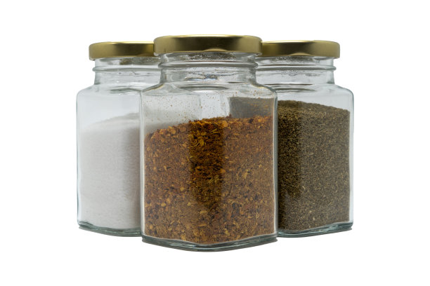 三个装有香料的玻璃罐。辣椒粉，盐和芹菜籽。隔离在白色与剪切路径。图片下载
