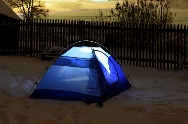 穿着户外服装的游客将直接睡在雪地上的蓝色帐篷里。支持大自然的装备，在离小屋不远的荒野中体验一次冒险。里面有手电筒。图片下载