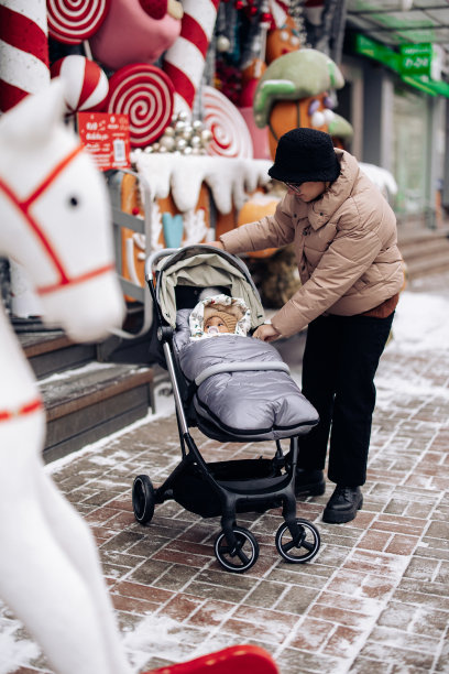 快乐的白人妇女带着婴儿走在圣诞集市上。图片下载