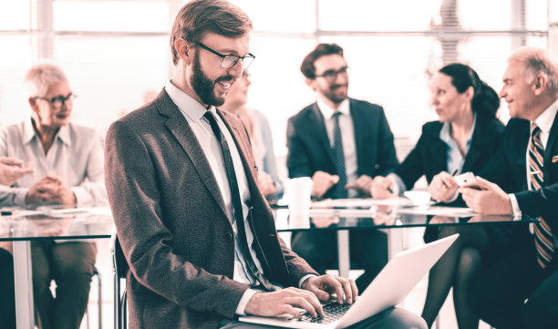 关闭了。微笑的商人在办公室使用笔记本电脑。图片下载