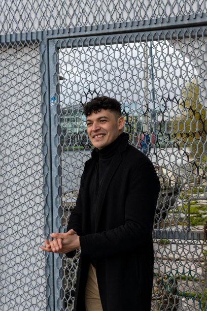 年轻的墨西哥绅士在优雅的黑色衣服微笑的金属栅栏背景图片下载