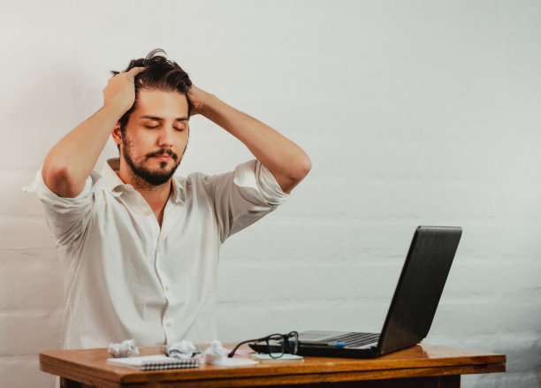 年轻的白人男性通过双手抱头，深呼吸来表现疲劳和压力图片下载