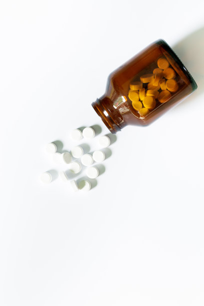 白色背景的药丸和药瓶，黄色的药瓶。白色背景的圆形白色药丸。图片下载