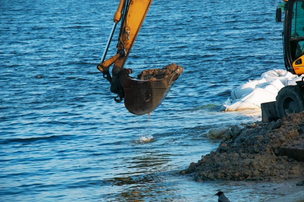 挖掘机加固路堤。液压挖掘机在河岸上工作。图片下载
