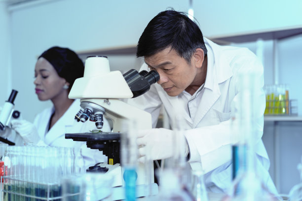 科学家在有试管背景的实验室使用显微镜。医疗保健技术和药物研发理念图片下载