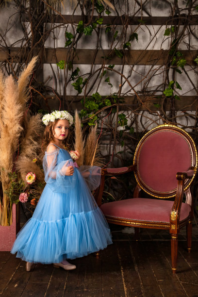 小女孩公主穿着艺术浅蓝色连衣裙，头上戴着花环，站在神秘装饰的房间里，看着相机。幻想艺术照片，童话概念。复制文本空格图片下载