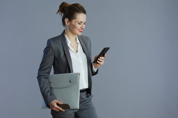 快乐时尚的女员工在灰色西装孤立的灰色图片下载