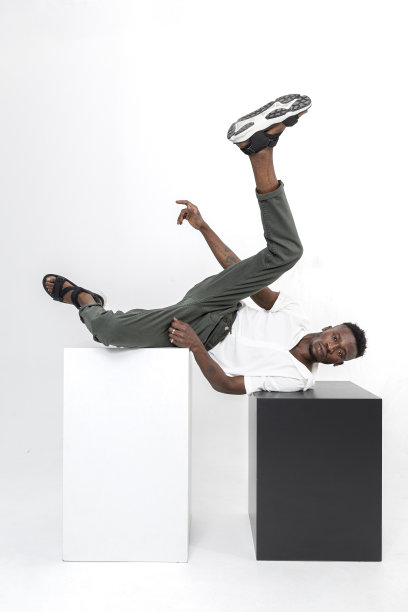 黑色英俊的非洲裔男子穿着白色衬衫，棕色织物裤子，黑色夏季凉鞋与立方体在工作室。图片下载