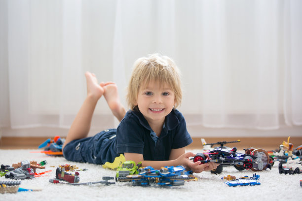 可爱的蹒跚学步的孩子，金发男孩，玩彩色塑料块，建筑玩具图片下载