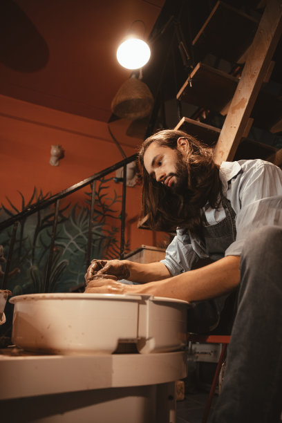 陶艺大师雕刻陶杯。手工壶艺术家制作与照顾垂直射击。图片下载