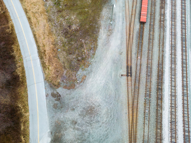 乡村道路和火车轨道之间的草地和落叶森林在秋季照片图片下载