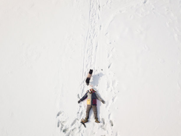 正上方，一个女人和她的狗躺在结冰的湖面上图片下载