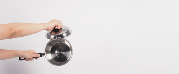 清洁锅的人在白色的背景上用方便的洗碗海绵清洁不粘锅，软的一面是黄色，硬的一面是绿色，以保证烹饪后的卫生。电锅图片下载