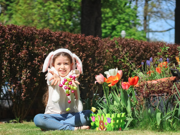 一个白人女孩穿着高领毛衣和牛仔裤，头上戴着兔子耳朵，扔着巧克力复活节彩蛋图片下载