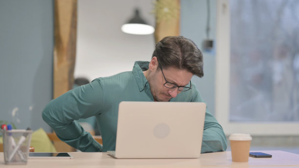 成年男子使用笔记本电脑时背部疼痛图片下载