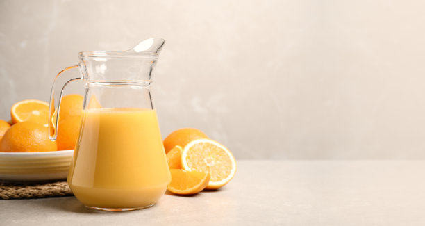 浅灰色的桌子上放着一壶橙汁和新鲜水果，还有文字空间。旗帜设计图片下载