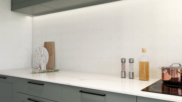 干净的黑色空间白色大理石厨房柜台，鼠尾草绿色橱柜，橱柜，感应灶台，方形白色瓷砖飞溅后墙图片下载