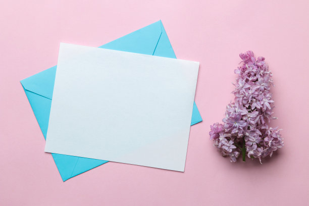 蓝色信封，空白文字和一支丁香枝在明亮的时尚粉色背景。俯视图图片下载