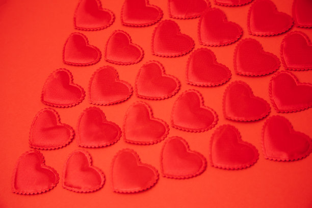 红色背景上的红色缎子心。情人节的背景。有选择性的重点图片下载