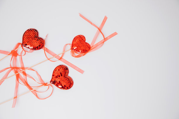 白色背景上镶着亮片的红心。情人节背景图片下载